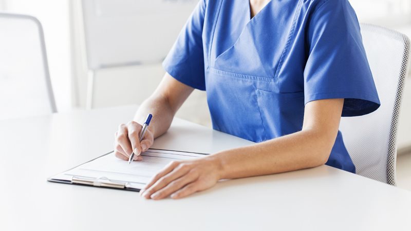 a healthcare worker is writing at a desk